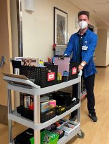 Young person pushing a cart of activity items in hospital hallway